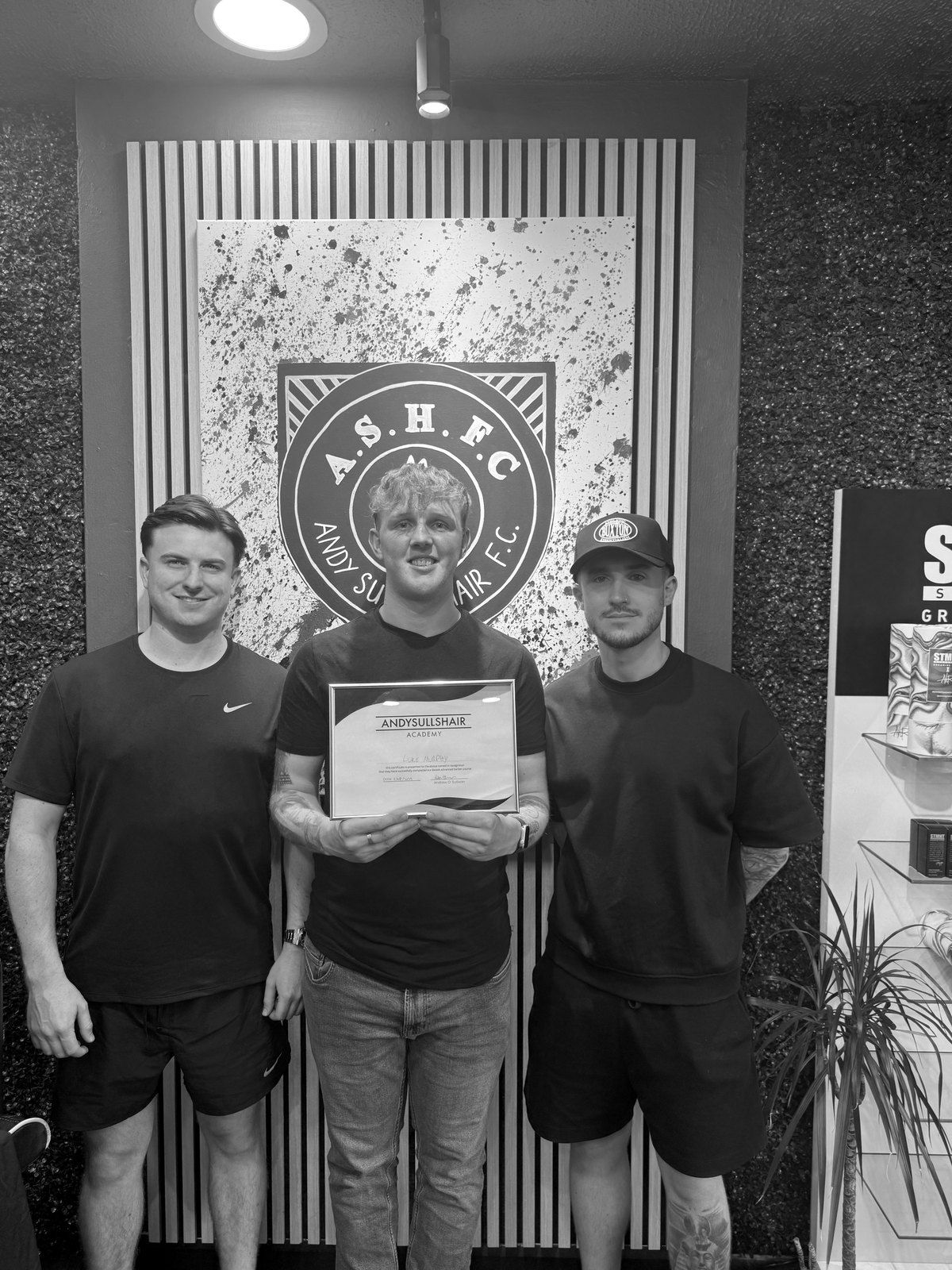 Andy with two graduates and their certificates in the shop