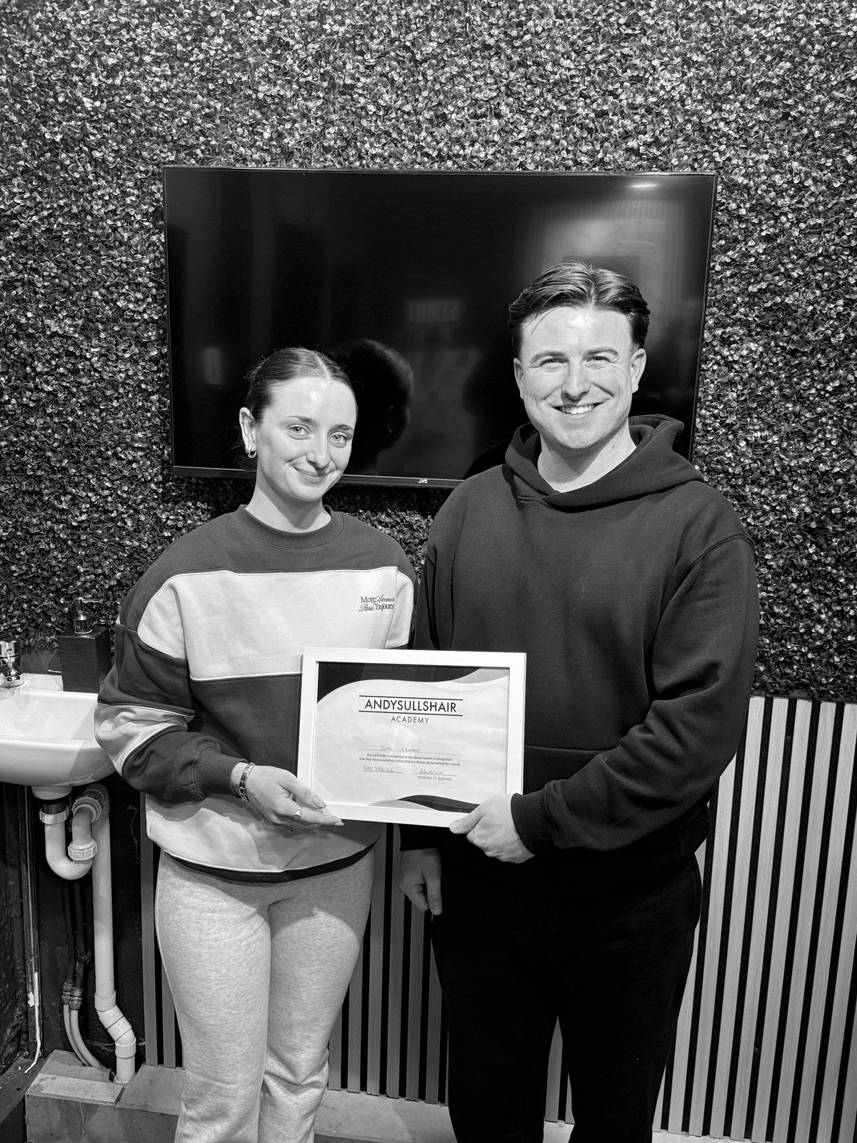 A graduate and Andy with her certificate in the shop